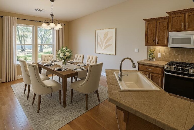 dining space with visible vents, light wood finished floors, a notable chandelier, and vaulted ceiling