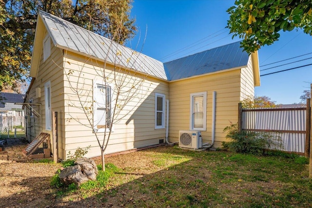 back of property with ac unit, metal roof, fence, and a lawn