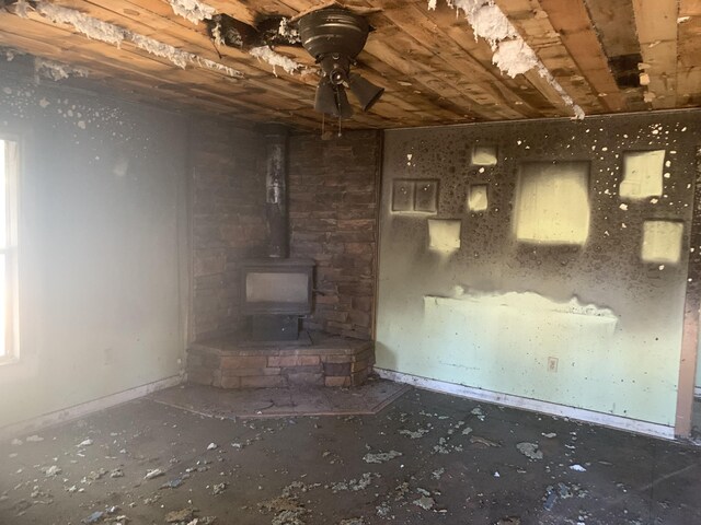 37183 Sandy Ln, Burney, CA 96013 - unfurnished living room with a ceiling fan, baseboards, a wood stove, and concrete flooring