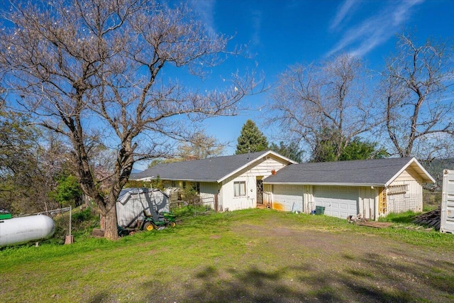 view of front of property with a garage, a front lawn, fence, and an outbuilding