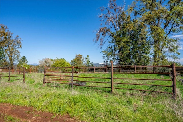 view of gate with a rural view, a mountain view, and fence