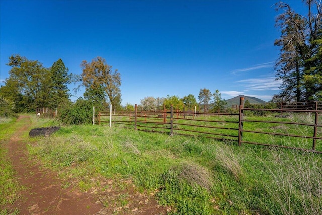 view of yard featuring a rural view, a mountain view, and fence