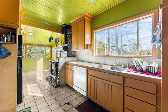 kitchen with dishwasher, a sink, tile counters, backsplash, and light tile patterned flooring