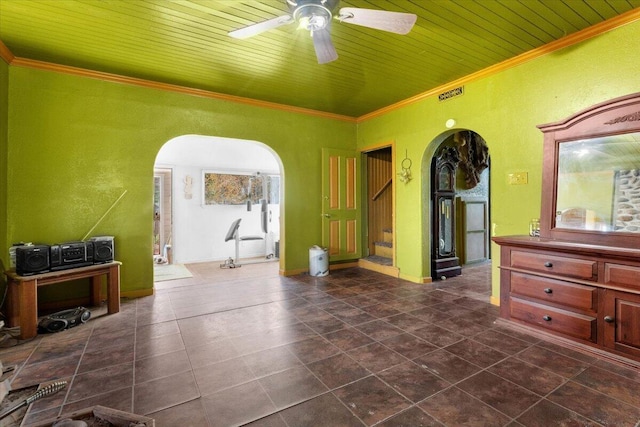 interior space featuring arched walkways, ceiling fan, dark tile patterned floors, crown molding, and stairs