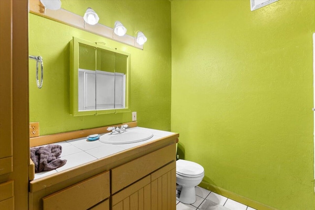 half bathroom with tile patterned flooring, vanity, baseboards, and toilet
