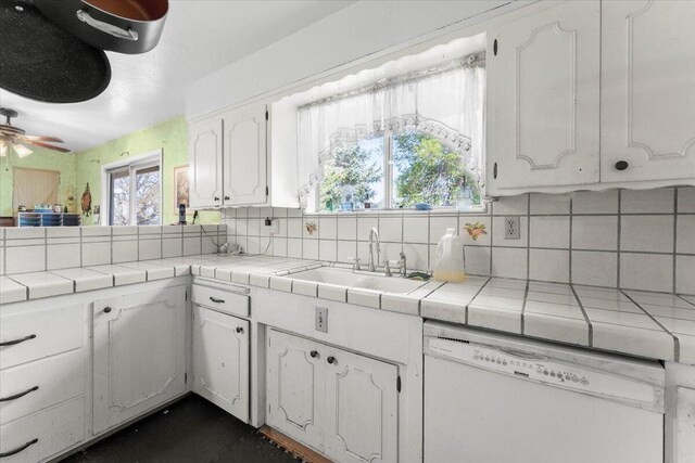 kitchen with tasteful backsplash, white cabinets, white dishwasher, a sink, and tile countertops
