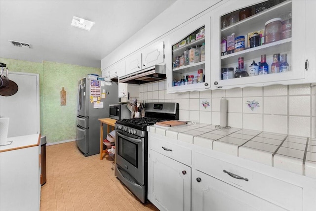 kitchen featuring tile countertops, white cabinetry, visible vents, under cabinet range hood, and appliances with stainless steel finishes