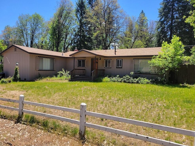 single story home with board and batten siding, a front yard, and fence