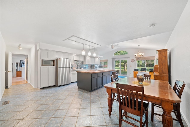 dining area with light tile patterned flooring, ceiling fan with notable chandelier, baseboards, vaulted ceiling, and visible vents