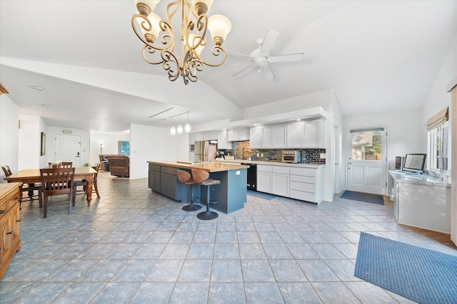 kitchen with light countertops, freestanding refrigerator, lofted ceiling, white cabinetry, and open floor plan