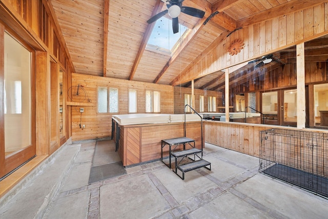 kitchen featuring vaulted ceiling with skylight, a kitchen island, a ceiling fan, wooden ceiling, and wooden walls