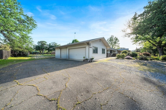 view of property exterior featuring a garage, aphalt driveway, and fence