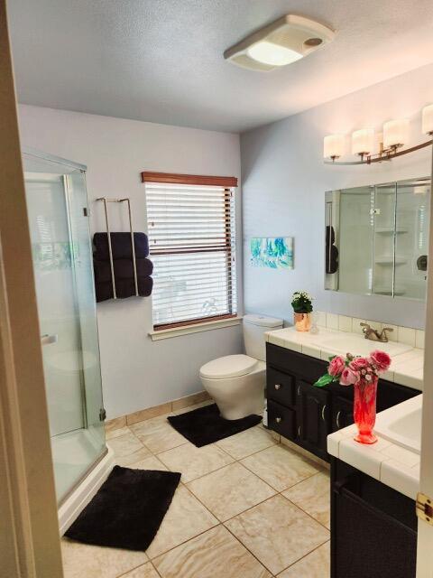bathroom featuring vanity, tile patterned floors, a shower stall, and toilet