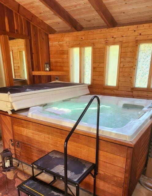 misc room featuring wooden ceiling, beamed ceiling, a jacuzzi, and wood walls