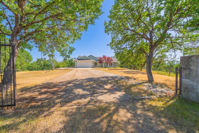 view of front of property with dirt driveway and a garage
