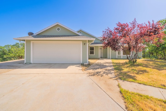 single story home with an attached garage, concrete driveway, a front yard, a porch, and roof with shingles