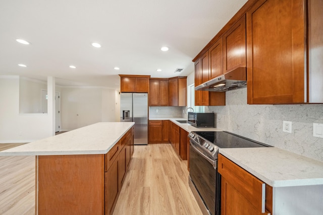 kitchen featuring a sink, stainless steel appliances, under cabinet range hood, a center island, and light wood-style floors