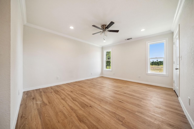 empty room featuring crown molding, light wood finished floors, and visible vents