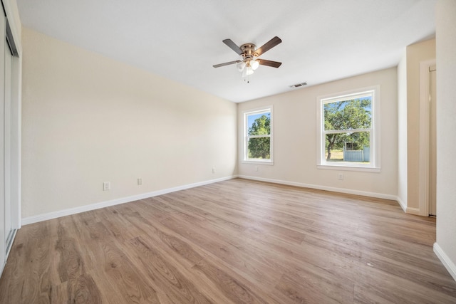 spare room featuring a ceiling fan, baseboards, light wood-type flooring, and visible vents