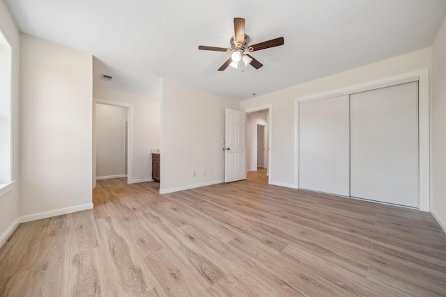 unfurnished bedroom with a closet, baseboards, ceiling fan, visible vents, and light wood-style floors
