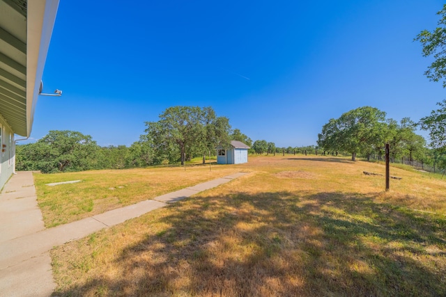 view of yard with a rural view, an outbuilding, and a storage unit