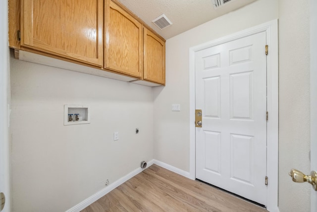 clothes washing area with cabinet space, visible vents, light wood-style flooring, electric dryer hookup, and hookup for a washing machine