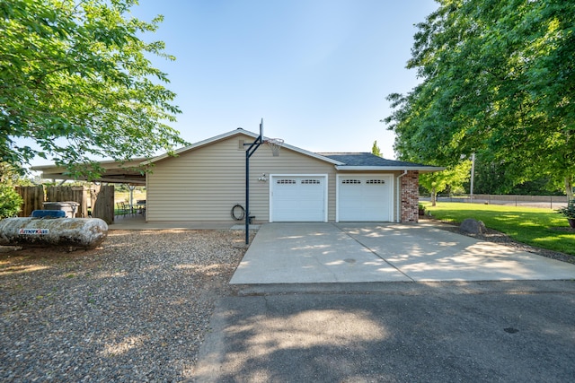 view of side of home with fence, brick siding, driveway, a garage, and a lawn