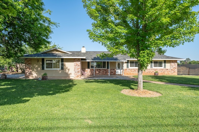 ranch-style house featuring a front lawn, brick siding, a chimney, and fence