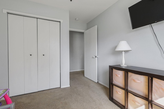 bedroom featuring a closet, light colored carpet, and baseboards