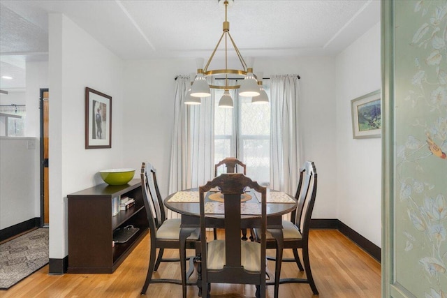 dining space with a notable chandelier, light wood-style floors, and baseboards