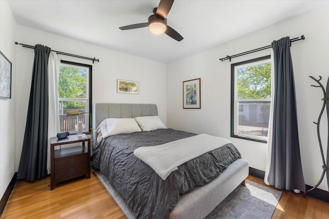 bedroom featuring ceiling fan, multiple windows, and light wood-style floors