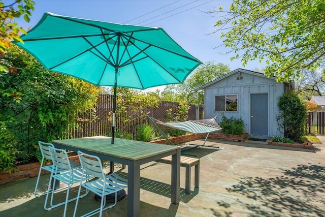 view of patio / terrace featuring an outdoor structure, outdoor dining space, and fence