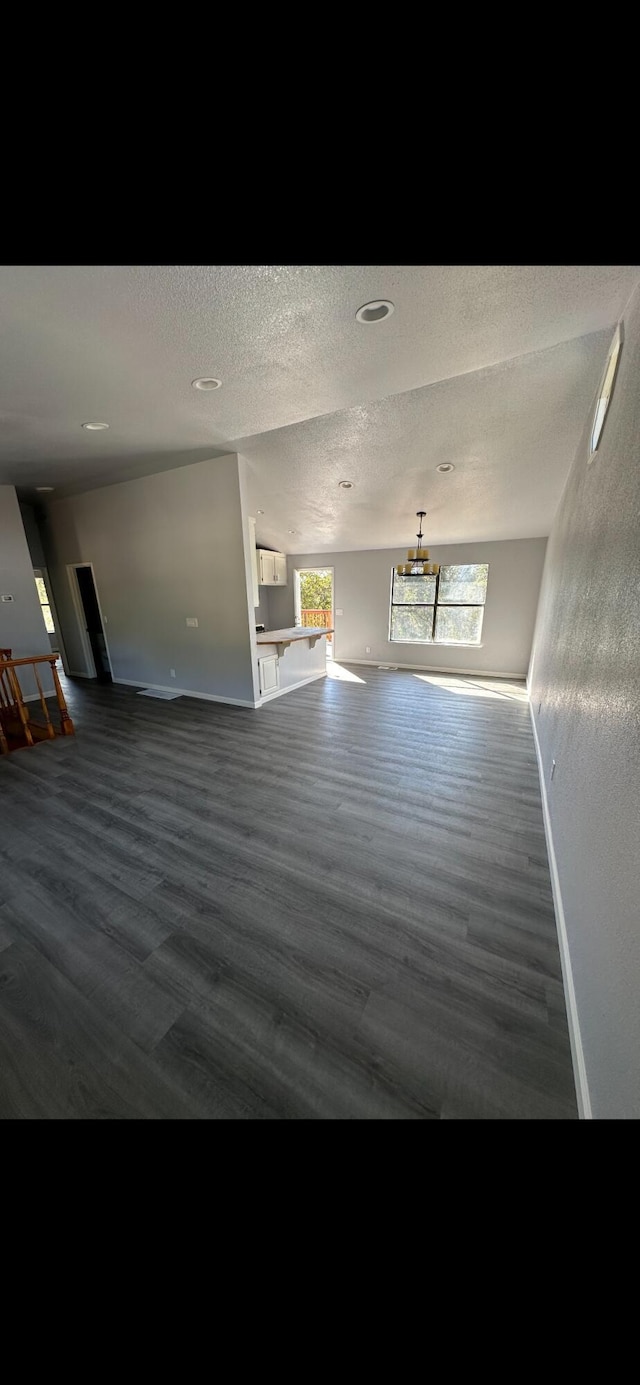 unfurnished living room featuring baseboards, a textured ceiling, and wood finished floors