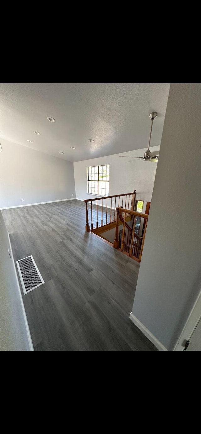 interior space featuring visible vents, baseboards, wood finished floors, and an upstairs landing