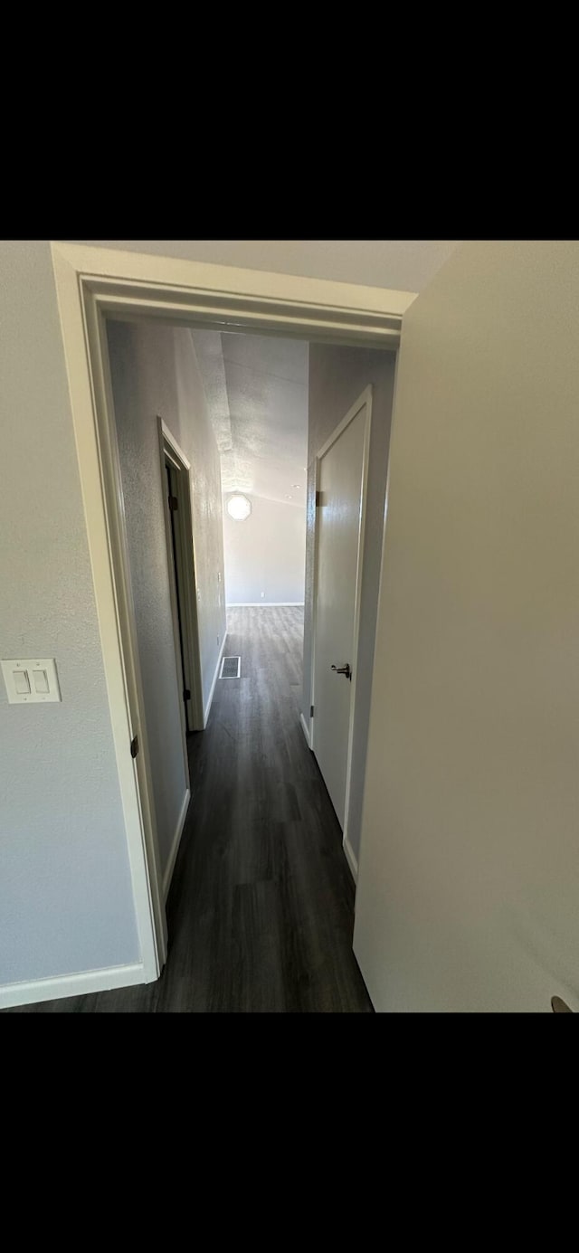 corridor featuring baseboards, visible vents, and dark wood-style floors