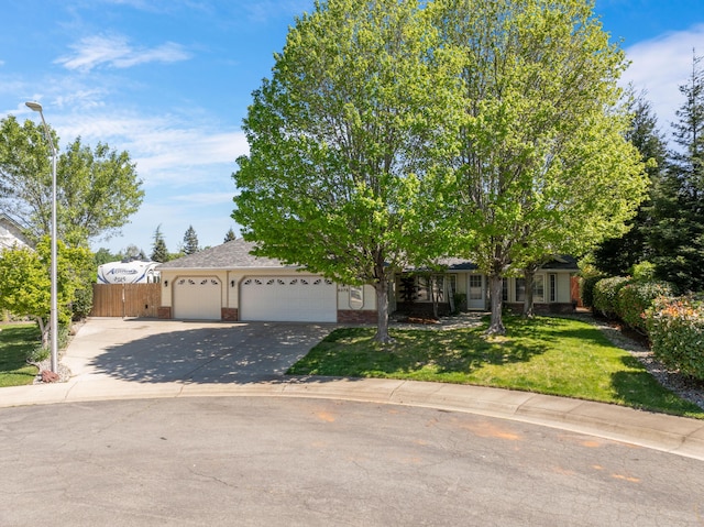 view of property hidden behind natural elements with a front lawn, a garage, driveway, brick siding, and fence