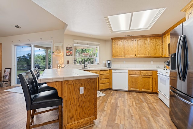 kitchen with a wealth of natural light, visible vents, white appliances, and light wood-style flooring