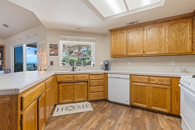 kitchen featuring visible vents, a sink, wood finished floors, and white appliances