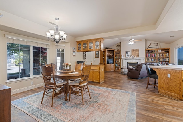 dining area with a glass covered fireplace, a healthy amount of sunlight, wood finished floors, and visible vents