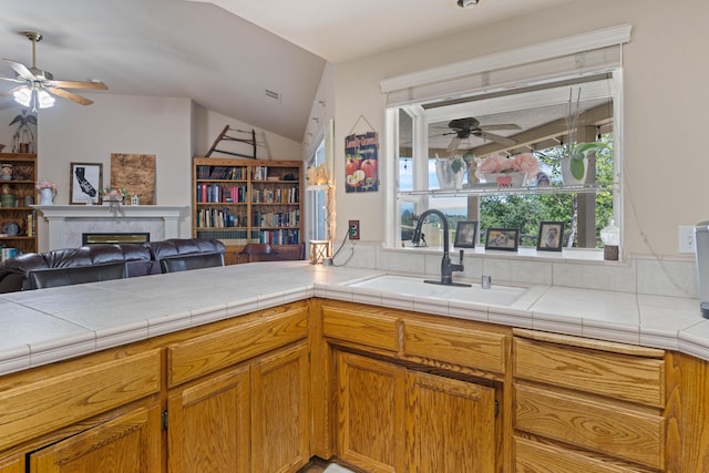 kitchen with a sink, a fireplace, ceiling fan, vaulted ceiling, and open floor plan