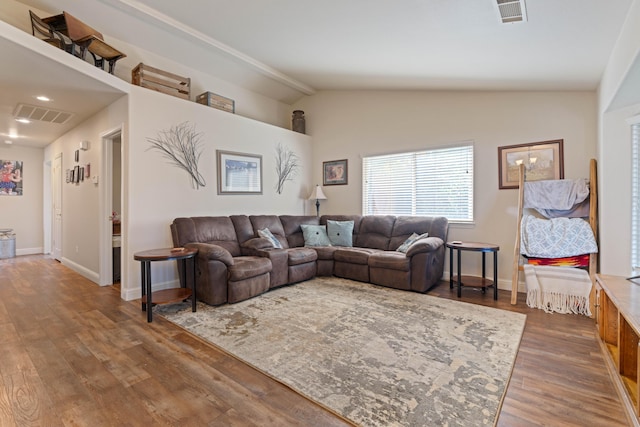 living area featuring lofted ceiling, wood finished floors, visible vents, and baseboards