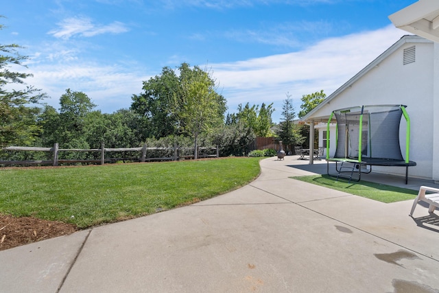 view of yard featuring a patio, a trampoline, and fence