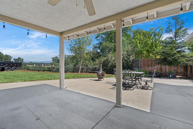 view of patio with fence, outdoor dining space, and a ceiling fan