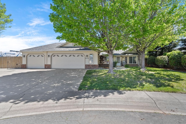 view of front facade featuring brick siding, fence, a front lawn, concrete driveway, and an attached garage
