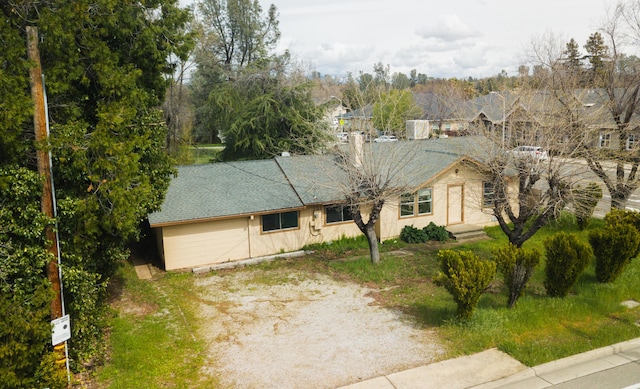 view of front of house featuring an attached garage, roof with shingles, and dirt driveway