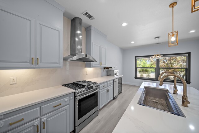 2120 Tradition Way, Redding, CA 96001 - kitchen featuring stainless steel gas range, wall chimney range hood, light wood finished floors, light countertops, and pendant lighting