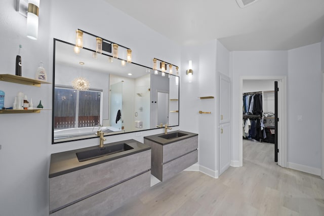 2120 Tradition Way, Redding, CA 96001 - full bathroom featuring a shower stall, wood finished floors, two vanities, a walk in closet, and a garden tub