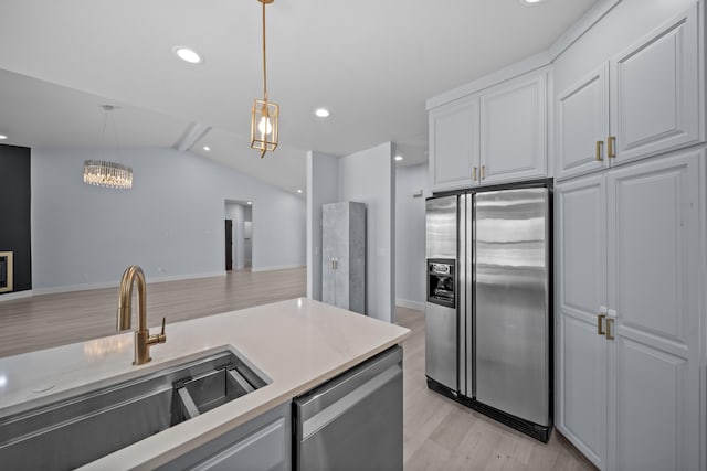 2120 Tradition Way, Redding, CA 96001 - kitchen with stainless steel appliances, vaulted ceiling, light wood-style floors, hanging light fixtures, and white cabinetry