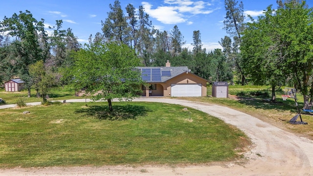 view of front of home featuring a shed, curved driveway, solar panels, and a front yard