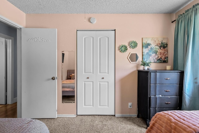 bedroom with a closet, carpet flooring, a textured ceiling, and baseboards